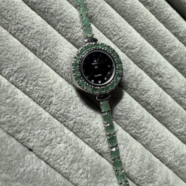 A silver watch set with emeralds
