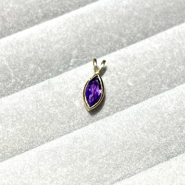 A gold pendant with an amethyst and a chain