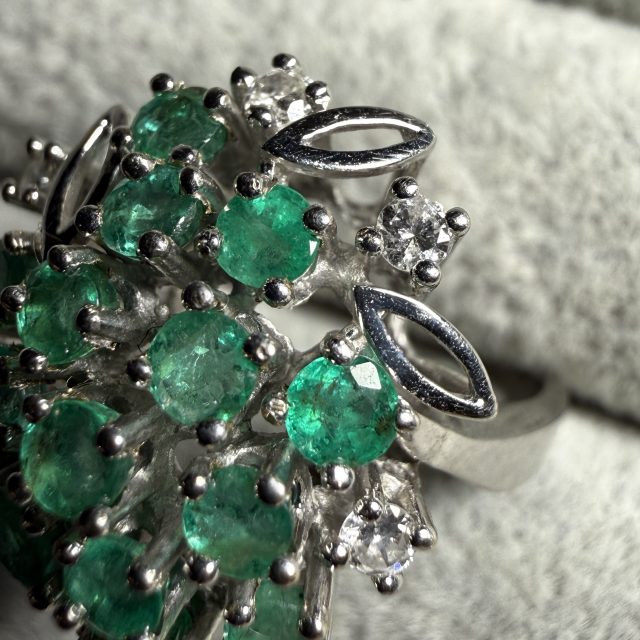 A gold ring set with emeralds and diamonds